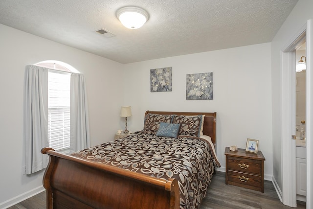 bedroom featuring dark wood finished floors, baseboards, and a textured ceiling