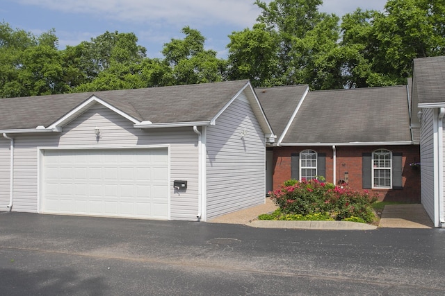 ranch-style home with a garage, asphalt driveway, and a shingled roof