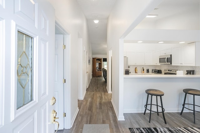foyer with dark wood-type flooring and baseboards