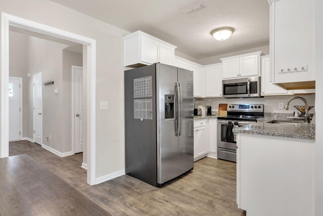 3507 Learning Ln, Murfreesboro, TN 37128 - kitchen featuring appliances with stainless steel finishes, a sink, light wood finished floors, white cabinetry, and light stone countertops