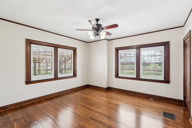spare room featuring healthy amount of natural light, wood finished floors, baseboards, and crown molding