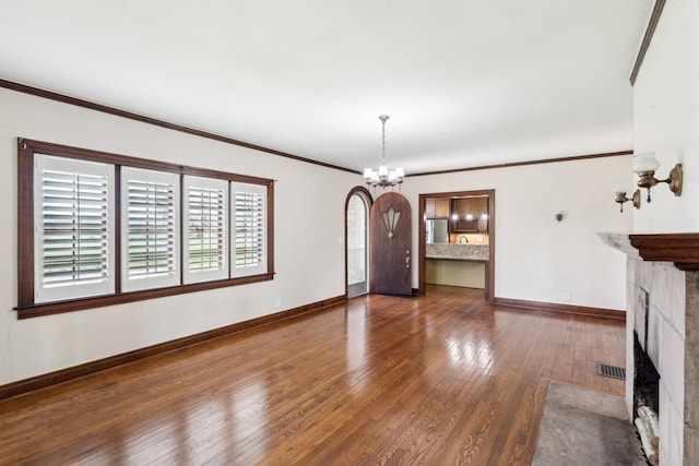 unfurnished living room with hardwood / wood-style flooring, a chandelier, a fireplace with flush hearth, baseboards, and crown molding