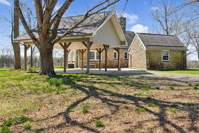 back of house featuring a chimney, a patio, and roof with shingles