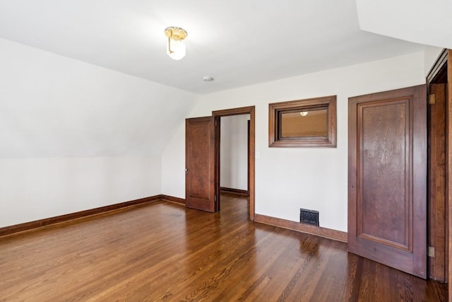 additional living space featuring dark wood-style flooring, baseboards, and lofted ceiling