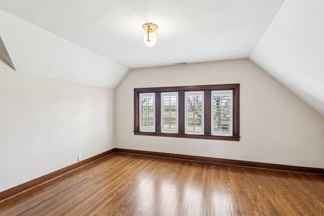 additional living space with lofted ceiling, wood finished floors, and baseboards