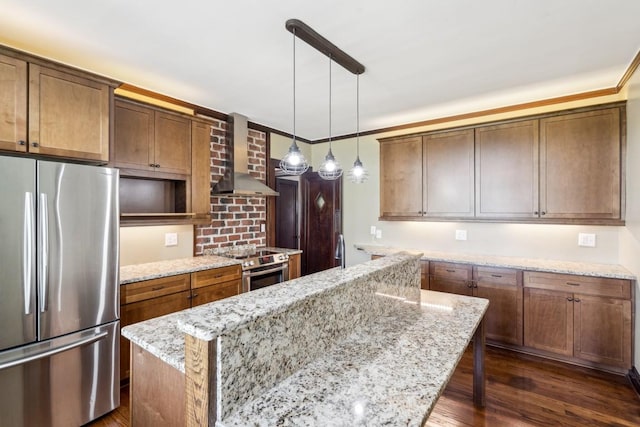 kitchen with appliances with stainless steel finishes, wall chimney range hood, a kitchen island, dark wood-type flooring, and light stone countertops