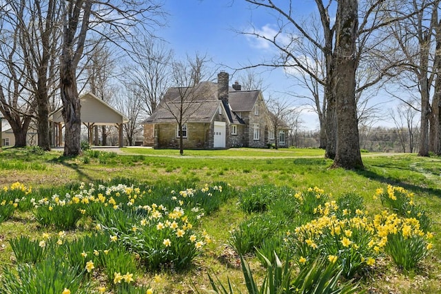 view of front of property featuring a chimney, a front lawn, and stone siding