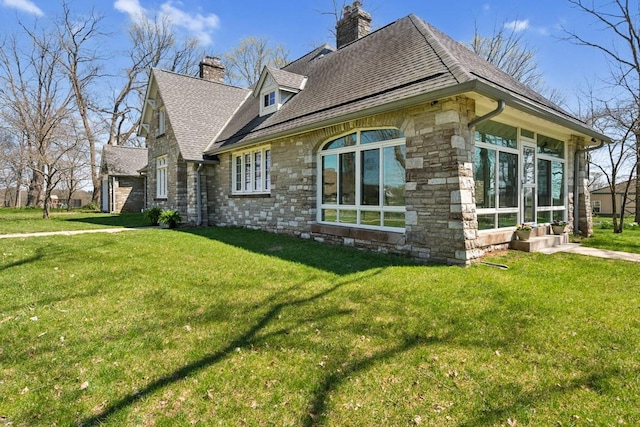 view of side of home with a chimney, a yard, stone siding, and roof with shingles