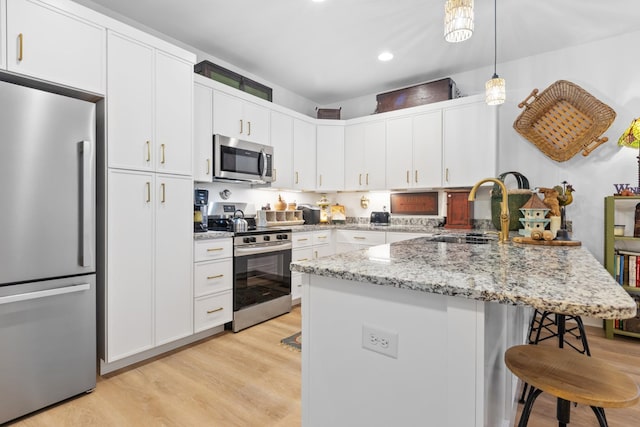 726 Morgan Ave, Woodbury, TN 37190 - kitchen with appliances with stainless steel finishes, a kitchen bar, a sink, light wood-type flooring, and a peninsula