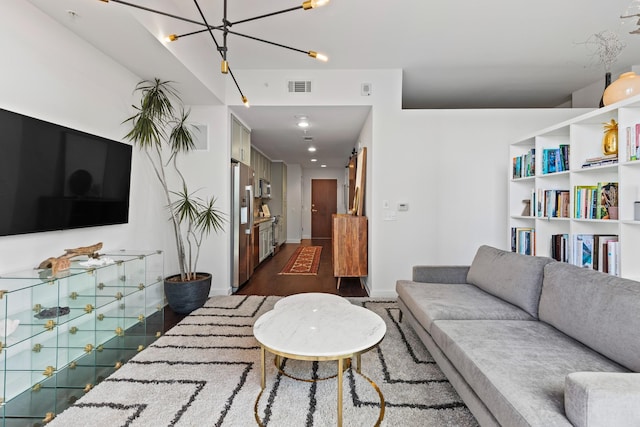 living area featuring dark wood-style flooring, baseboards, and a chandelier