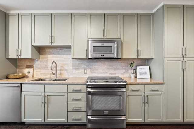 kitchen with appliances with stainless steel finishes, a sink, tasteful backsplash, and light stone counters