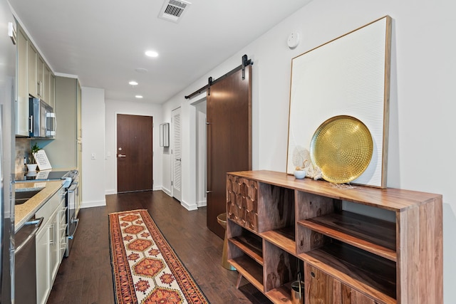 kitchen featuring stainless steel appliances, dark wood-type flooring, a barn door, recessed lighting, and baseboards