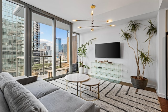 living room with a chandelier, wood finished floors, baseboards, and expansive windows