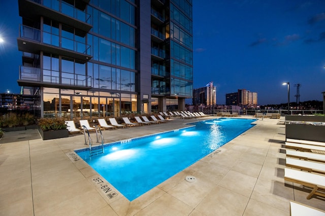 pool at twilight featuring a community pool and a patio