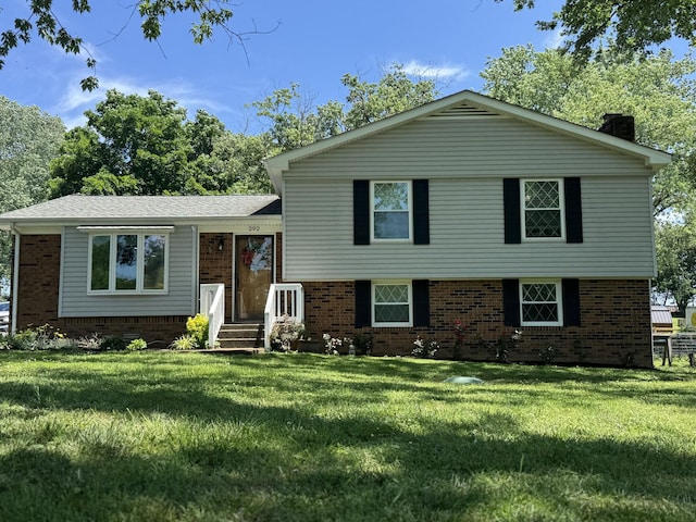 tri-level home featuring brick siding, a chimney, and a front lawn