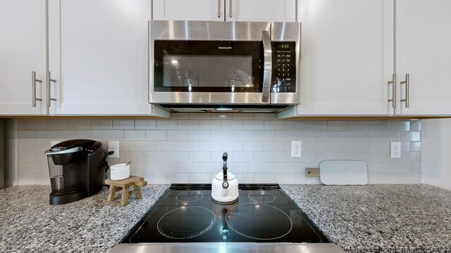 1768 Frodo Way, Murfreesboro, TN 37128 - kitchen view of stainless steel microwave, cooktop, white cabinets, light stone counters, and backsplash