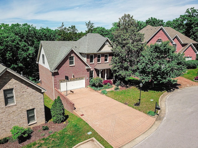 view of front of property with an attached garage, concrete driveway, brick siding, and a front yard