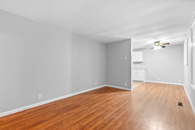 unfurnished living room featuring light wood-style flooring, baseboards, and a ceiling fan