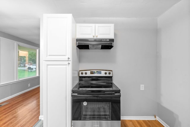 kitchen with under cabinet range hood, stainless steel range with electric cooktop, light wood finished floors, white cabinetry, and baseboards