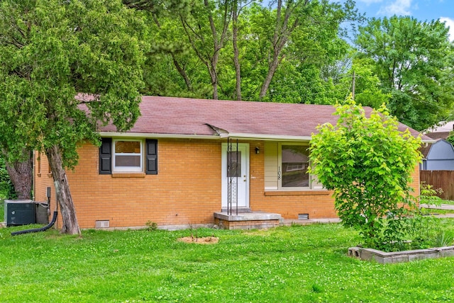 view of front facade featuring brick siding, a front lawn, central AC unit, and roof with shingles