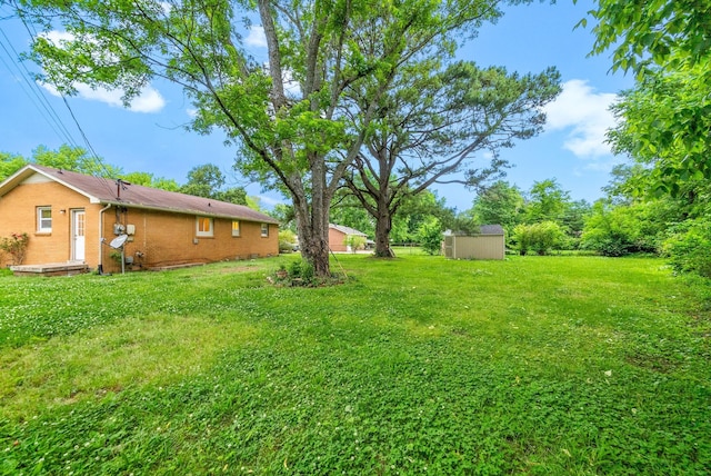 view of green lawn with a storage unit and an outbuilding