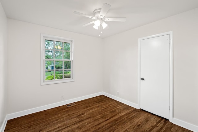 empty room featuring baseboards, dark wood-style flooring, and a ceiling fan