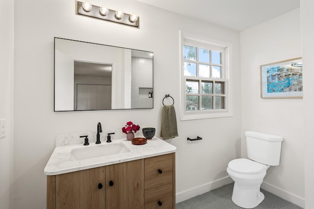 bathroom with toilet, baseboards, vanity, and tile patterned floors