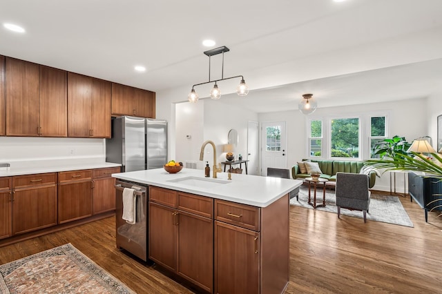 kitchen featuring stainless steel appliances, a sink, light countertops, dark wood finished floors, and decorative light fixtures