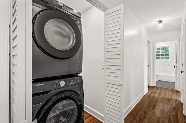 laundry room with stacked washer / dryer, dark wood-style floors, and baseboards
