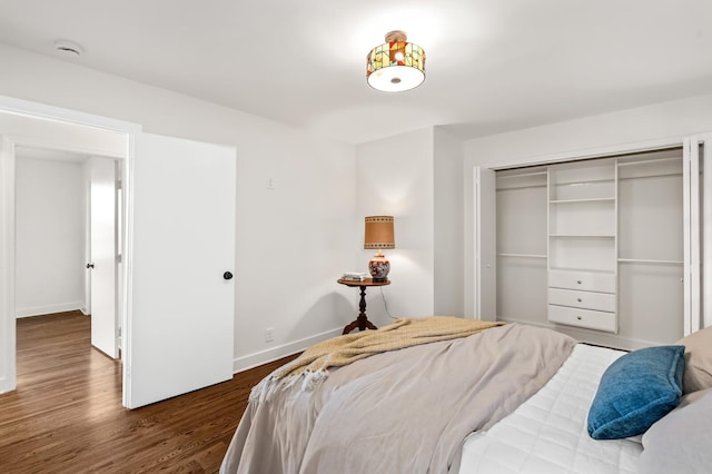 bedroom with wood finished floors, baseboards, and a closet