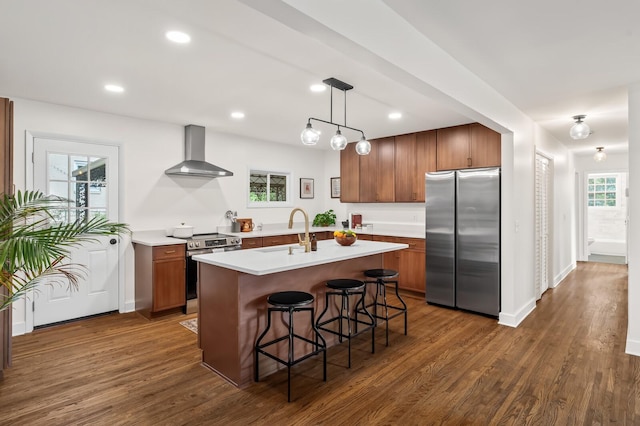 kitchen with appliances with stainless steel finishes, wall chimney exhaust hood, a sink, dark wood-style floors, and recessed lighting