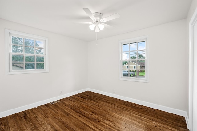 empty room with plenty of natural light, baseboards, and dark wood finished floors