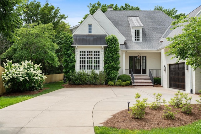 modern inspired farmhouse with concrete driveway, a garage, a standing seam roof, roof with shingles, and a chimney