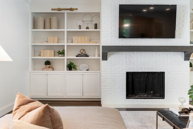 living room with baseboards, built in features, and a fireplace