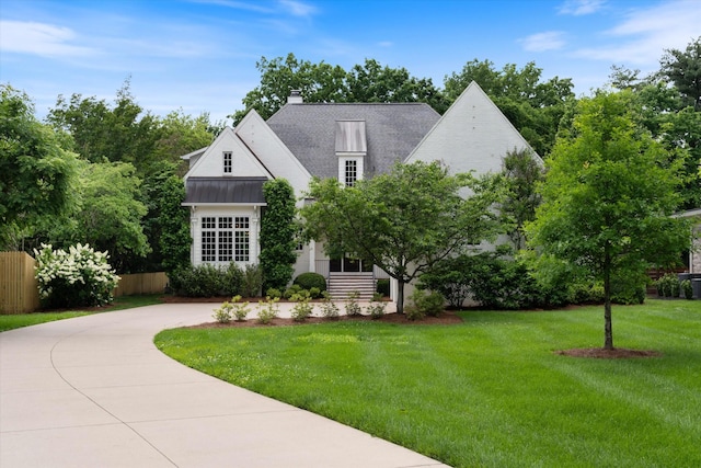 view of front facade with a standing seam roof, a chimney, metal roof, and curved driveway