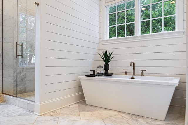 bathroom with marble finish floors, a stall shower, a freestanding bath, and wooden walls