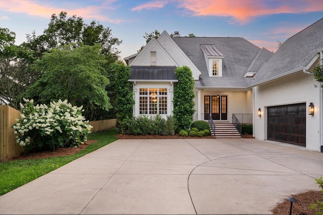 view of front of property featuring fence, concrete driveway, an attached garage, a standing seam roof, and a chimney