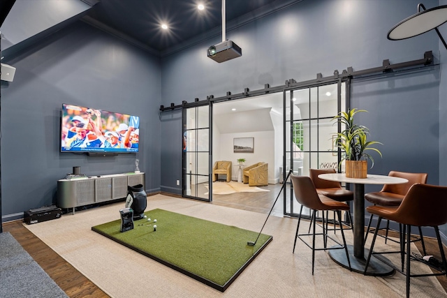 workout room featuring a high ceiling, a barn door, baseboards, recessed lighting, and wood finished floors