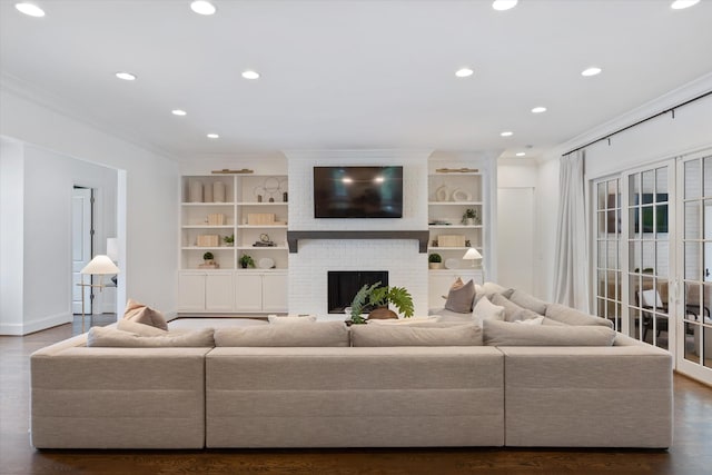 living room with crown molding, recessed lighting, wood finished floors, a fireplace, and built in shelves