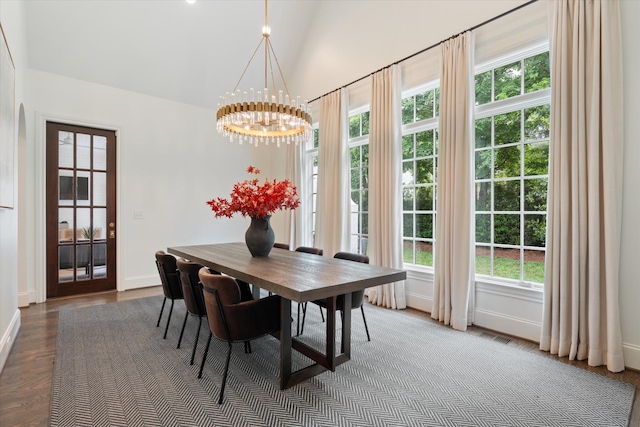 dining space with a chandelier, baseboards, lofted ceiling, and wood finished floors
