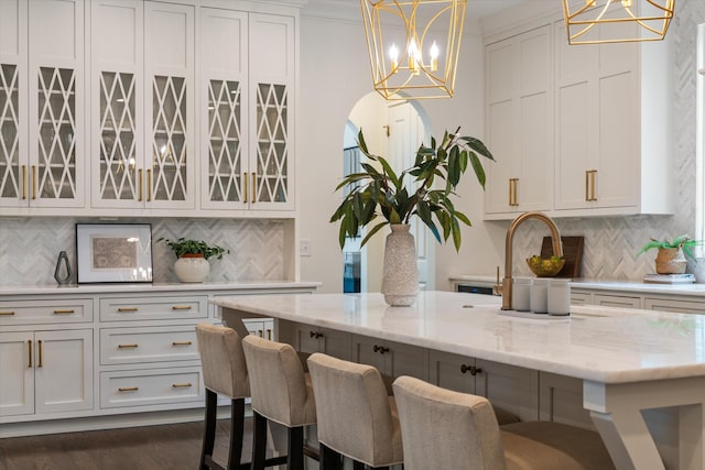 kitchen with a chandelier, a breakfast bar, light stone countertops, and backsplash