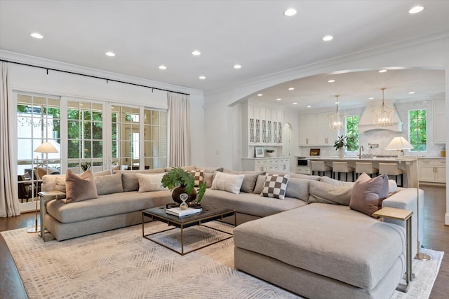 living area featuring crown molding, wood finished floors, arched walkways, and recessed lighting