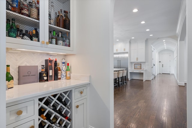 indoor dry bar with recessed lighting, dark wood finished floors, arched walkways, baseboards, and tasteful backsplash