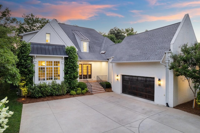 modern farmhouse style home featuring driveway, a garage, roof with shingles, a porch, and brick siding