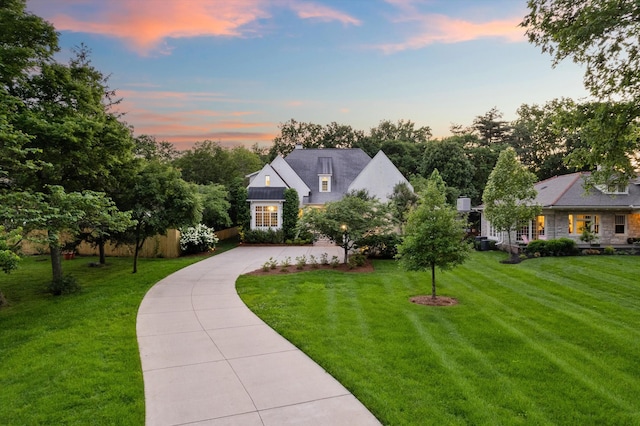 view of front of house with curved driveway, a lawn, and stone siding