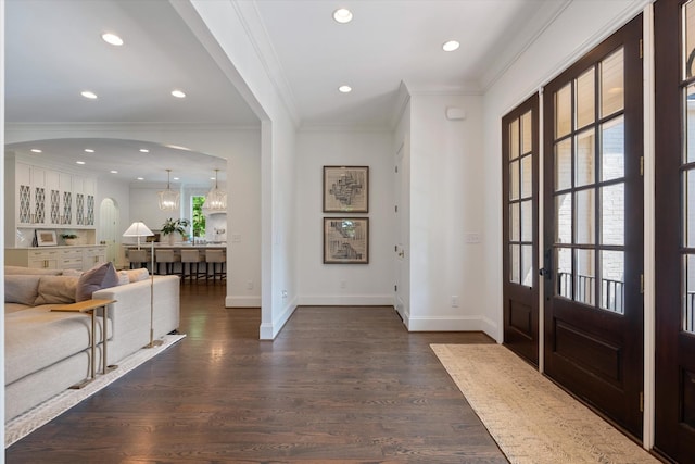 foyer entrance with dark wood-type flooring, crown molding, baseboards, arched walkways, and recessed lighting