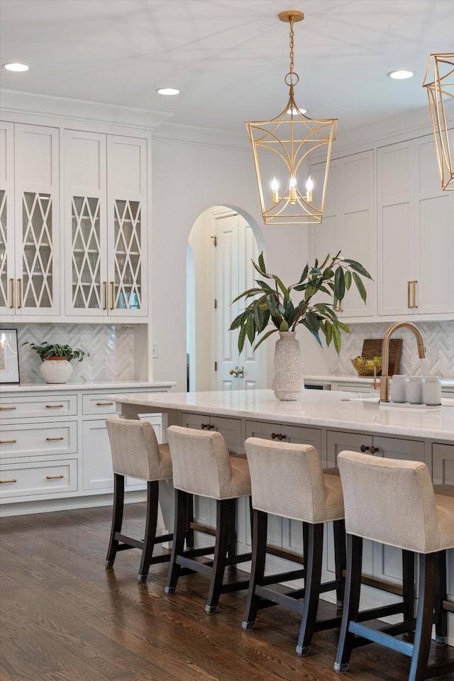dining space with ornamental molding, recessed lighting, arched walkways, dark wood finished floors, and a chandelier