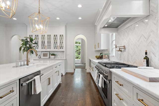 kitchen featuring appliances with stainless steel finishes, arched walkways, crown molding, a chandelier, and a sink