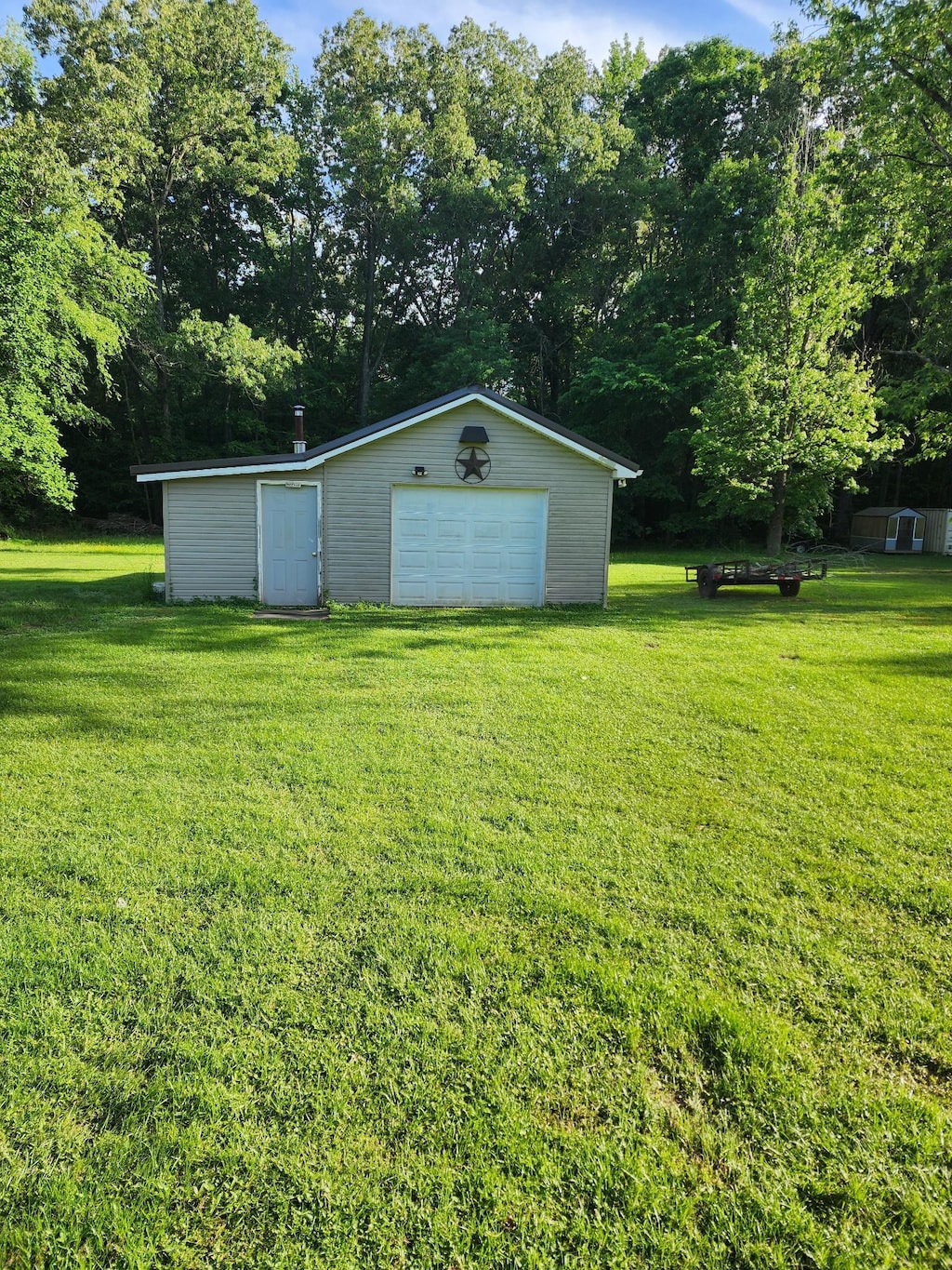 348 Leader Dr, New Johnsonville, TN 37134 - view of grassy yard featuring an outdoor structure, a garage, and view of wooded area