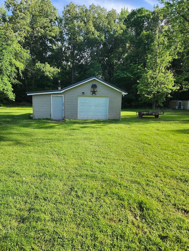 348 Leader Dr, New Johnsonville, TN 37134 - view of grassy yard featuring an outdoor structure, a garage, and view of wooded area